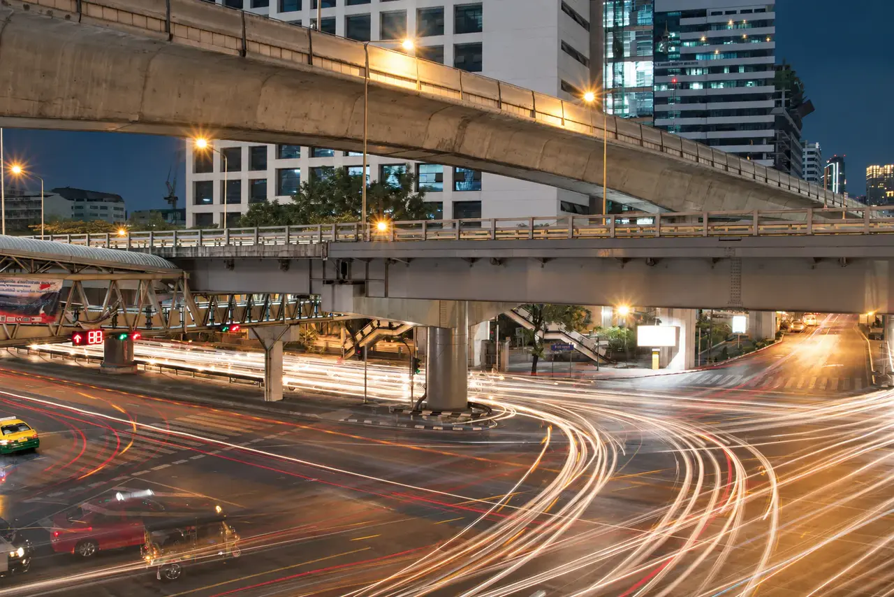 Traffic moving through a Bangkok intersection beneath elevated rail lines
